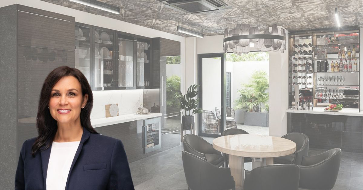 Smiling woman in a navy blazer and white blouse standing in front of a modern office space