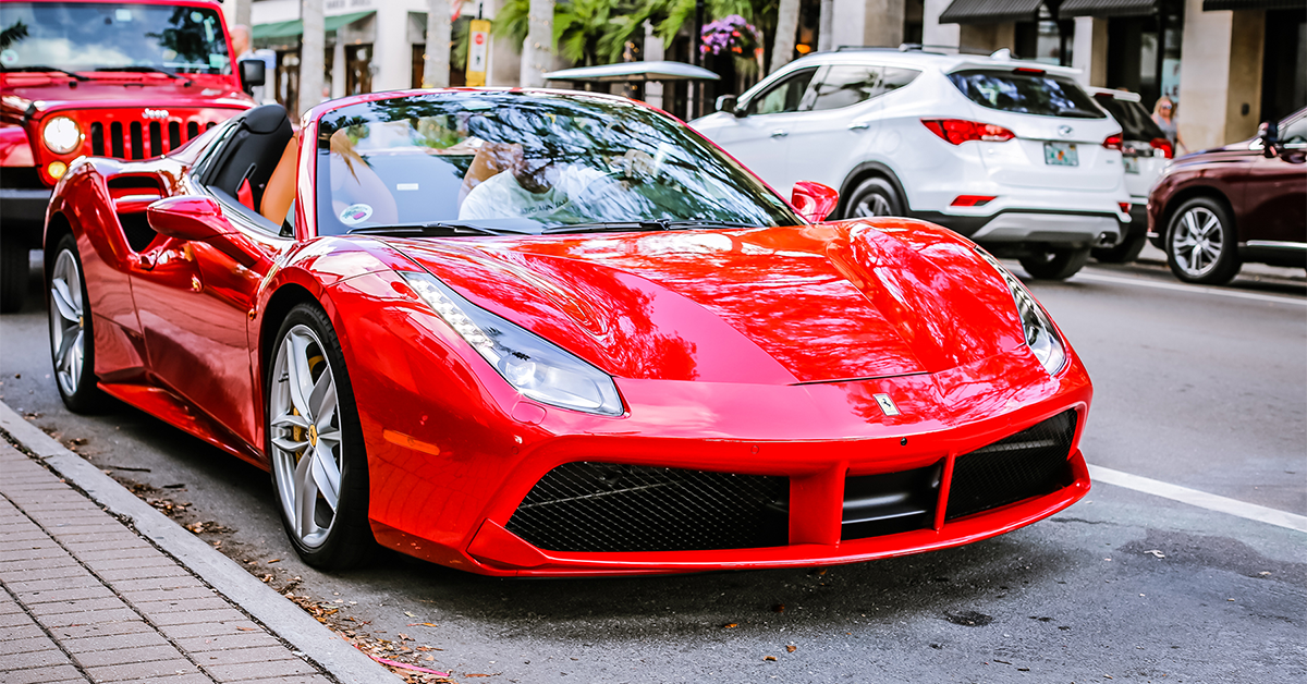 Red exotic sports car parked along a city street.