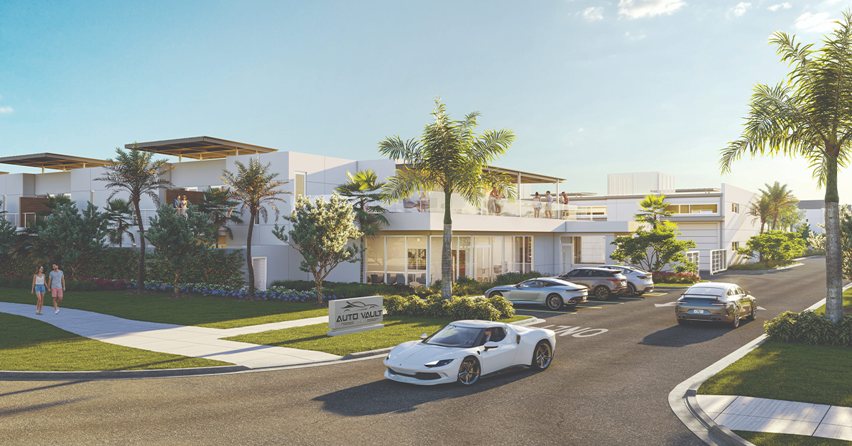 Modern auto vault entrance with glass facade, palm trees, and several parked sports cars.